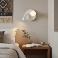 Biały kinkiet SOLE nad stolikiem nocnym